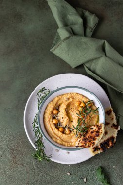 Biberiyeli klasik humus, yassı ekmek, haşlanmış nohut ve zeytinyağı, yeşil taş arka plan. Geleneksel Orta Doğu atıştırması. Üst görünüm.