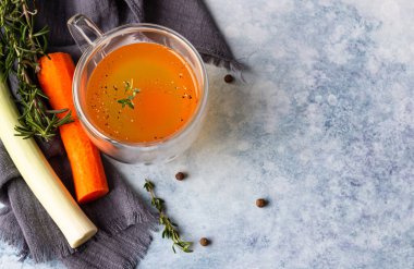 Cam bardak ve sebze içinde ev yapımı kemik suyu, mavi beton arka plan. Ceset için kolajen kaynağı. Seçici odaklanma. Üst görünüm.