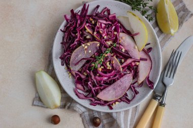 Kırmızı lahana, armut ve limon ve zeytinyağı soslu fındık salatası. Işık taşı arka planı. Vejetaryen yemeği. Seçici odaklanma. Üst görünüm.