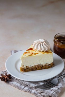 Beyaz seramik tabakta tuzlu karamelli ve kremalı havuçlu vanilyalı cheesecake, açık beton zemin.