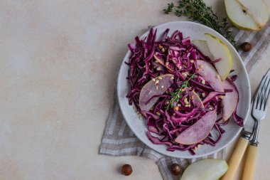 Kırmızı lahana, armut ve limon ve zeytinyağı soslu fındık salatası. Işık taşı arka planı. Vejetaryen yemeği. Üst görünüm.