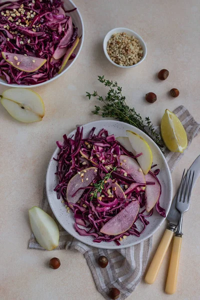 Kubis merah, salad pir dan hazelnut dengan lemon dan saus minyak zaitun. Latar belakang batu cahaya. Makanan vegetarian. Tampilan atas. — Stok Foto
