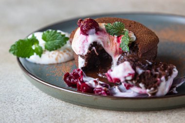 Krema, kiraz ve nane ile servis edilen geleneksel Fransız çikolatalı pasta. Çikolatalı şeker. Çikolatalı Lav keki. Seçici odak.