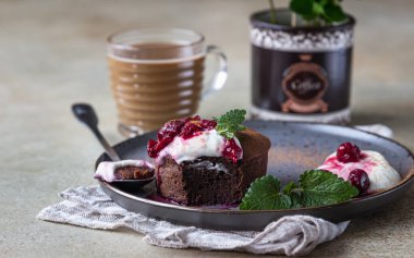 Mini çikolatalı kek ya da kremalı, kirazlı ve naneli kek seramik tabakta ve bir fincan kahveyle. Çikolatalı şeker. Kahvaltı ya da kadınlar için tatlı ya da anneler günü. Seçici odak.