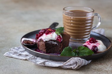 Mini çikolatalı kek ya da kremalı, kirazlı ve naneli kek seramik tabakta ve bir fincan kahveyle. Çikolatalı şeker. Kahvaltı ya da kadınlar için tatlı ya da anneler günü. Seçici odak.