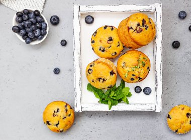 Hafif ahşap tepside kekik, nane ve taze böğürtlenli yabanmersinli kek. Gri arka plan. Üst görünüm.