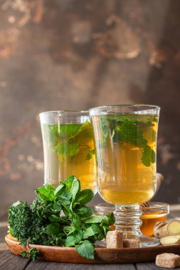 Soğuk günler için sıcak bitkisel içeceklerin bardaklara doldurulması. İki bardak nane, kekik ve ballı zencefil çayı. Seçici odak.