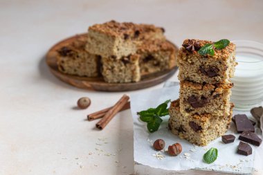 Çikolatalı, fındıklı yulaf ezmesi kareleri, çikolata ve nane parçaları, açık beton arka plan. Diyet çikolatalar. Kahvaltı ya da tatlı için sağlıklı fırın.
