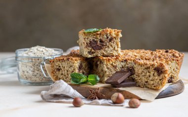 Çikolatalı, fındıklı yulaf ezmesi kareleri, çikolata ve nane parçaları, açık beton arka plan. Diyet çikolatalar. Kahvaltı ya da tatlı için sağlıklı fırın.