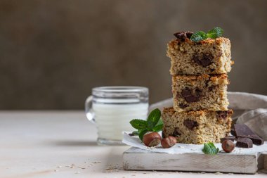 Çikolatalı yulaf ezmesi kareleri ve bir fincan süt, açık beton arka plan. Diyet çikolatalar. Kahvaltı ya da tatlı için sağlıklı fırın.