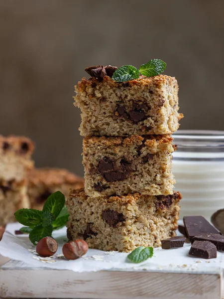 Çikolatalı yulaf ezmesi kareleri ve bir fincan süt, açık beton arka plan. Diyet çikolatalar. Kahvaltı ya da tatlı için sağlıklı bir fırın. Seçici odak.