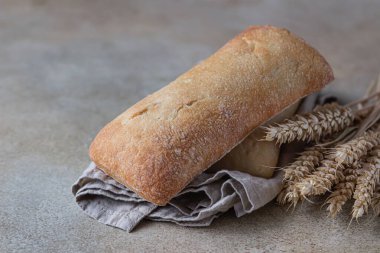 Keten peçetede çıtır İtalyan ciabatta ekmeği, taş zemin. Seçici odak.