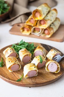 Hamurda ev yapımı sosis, susamlı, domates soslu, hafif taşlı arka planda. Battaniyeli domuzlar. Fast food. Seçici odak.