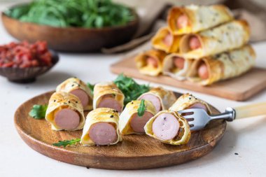 Hamurda ev yapımı sosis, susamlı, domates soslu, hafif taşlı arka planda. Battaniyeli domuzlar. Fast food. Seçici odak.