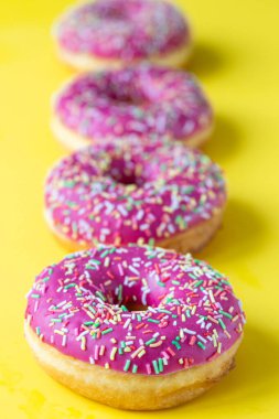 Sarı arka planda renkli serpiştirilmiş pembe jöleli çörekler. Minimalist bir kavram. Seçici odak.