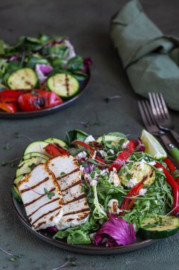 Izgara halloumi peynirli salata, ızgara sebze ve yeşil karışık salata yaprakları, yeşil beton arka plan. Vejetaryen gıda konsepti. Seçici odak.