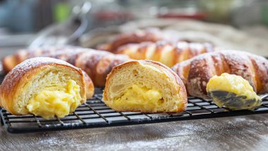 Siyah metal ızgarada pudra şekerle doldurulmuş kremalı taze maya çörekleri. Vanilya kremalı çörekler. Seçici odak.