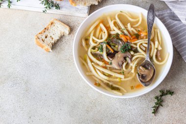 Mantarlı vejetaryen şehriye çorbası ve kekik ile servis edilen sebzeler, açık beton arka plan. Seçici odaklanma. Üst görünüm.