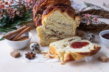 Tarçınlı babka ya da reçelli brioche ekmeği. Paskalya arkaplanı, bıldırcın yumurtaları, çiçekler ve el yapımı dal çelenkleri. Tarçınlı ekmek..
