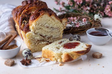 Tarçınlı babka ya da reçelli brioche ekmeği. Paskalya arkaplanı, bıldırcın yumurtaları, çiçekler ve el yapımı dal çelenkleri. Tarçınlı ekmek. Seçici odak.