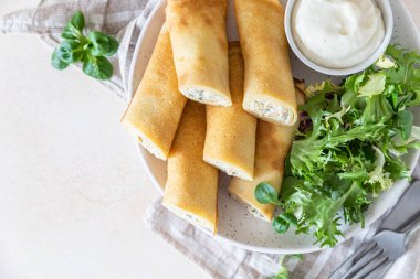 Tuzlu krepler mi yoksa yeşil salata ve beşamel sosuyla servis edilen tavuklu ince krepler mi? Seçici odak.