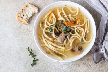 Mantarlı vejetaryen şehriye çorbası ve kekik ile servis edilen sebzeler, açık beton arka plan. Seçici odaklanma. Üst görünüm.