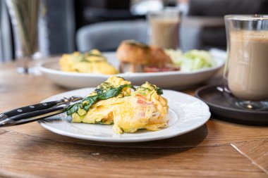 Tahta masada ıspanaklı omlet ve tostla servis edilen domatesler, salata yaprakları ve domates sosu. Sağlıklı kahvaltı ya da kafede kahvaltı. Güneşli bir sabah. Seçici odak.