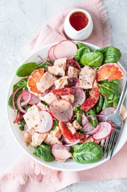 Somon, ıspanak, turp ve portakal sosuyla servis edilen kırmızı portakallı taze salata, açık beton arka plan. Seçici odaklanma. Üst görünüm.