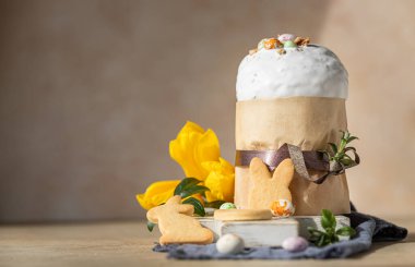 Geleneksel Ortodoks tatlı ekmeğiyle Paskalya kompozisyonu. Kulich krema, şeker şekilli yumurta, paskalya kurabiyesi ve lale ile süslenmiş. Seçici odak.