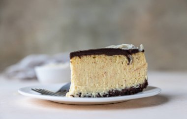 Çikolata jöleli ve bademli fırınlanmamış kremalı cheesecake dilimi, açık beton arka plan. Seçici odak.