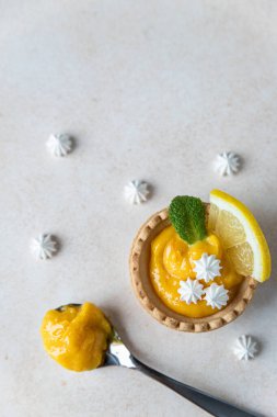 Limonlu mini tart, nane ve limon dilimleri, mini krema, açık beton arka plan. Üst Manzara. Uzayı kopyala Seçici odak.