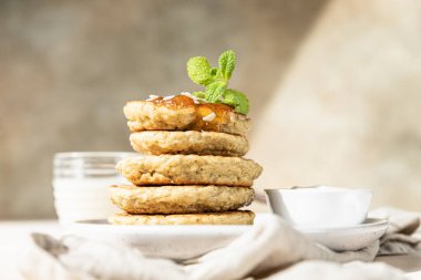 Kahvaltıda, fındık, reçel ve nane ile süslenmiş vejetaryen yulaf ezmeli krep yığını. Seçici odak.