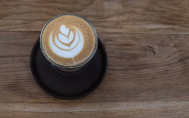 Kahve ya da kafedeki ahşap masada, cam fincanda latte sanatıyla kapuçino. Seçici odak.