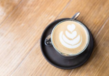 Kahve ya da kafedeki ahşap masada, cam fincanda latte sanatıyla kapuçino. Seçici odak.