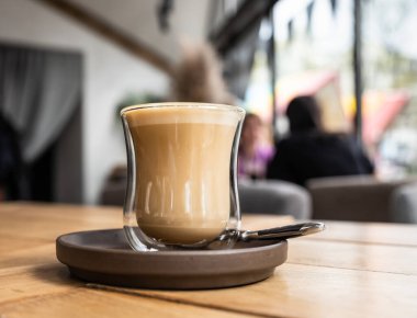 Kafede ya da kafede, ahşap masanın üzerinde cam bardakta kapuçino. Seçici odak.