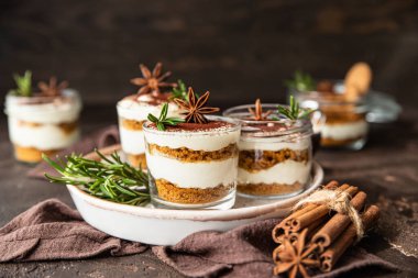 Cam kavanozda, biberiye, anason ve koyu arkaplanla süslenmiş kurabiye parçalı kremalı tatlı. Peynirli kek, çerez ya da puding yok..