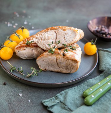 Izgara tavuk ya da hindi göğsü, kiraz domatesli ve kekik yeşil taş zemin üzerinde seramik bir tabakta..