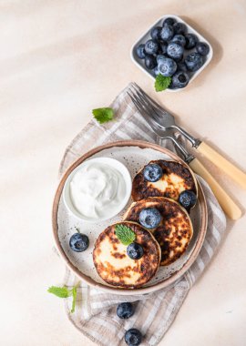 Kızarmış süzme peynirli krep ya da taze yaban mersinli börek ve ekşi krema. Glütensiz. Ukrayna ve Rus mutfağının geleneksel kahvaltısı. 