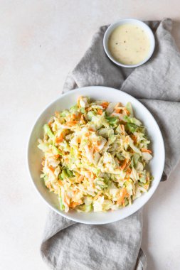 Lahana salatası. Parçalanmış beyaz lahana salatası, rendelenmiş havuç ve turuncu mayonez soslu ravent, açık beton arka plan..