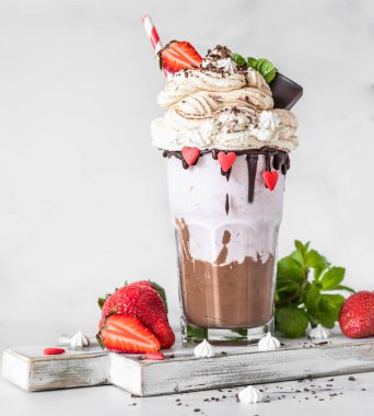 Çikolata ve çilekli milkshake ile birlikte dondurma ve krema, mini krema, çikolata, çilek ve naneli bardakta servis edilir. Seçici odak.