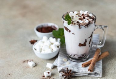 Marshmallow, tarçın ve nane arkaplanlı, cam bardakta sıcak çikolata ya da kakao..