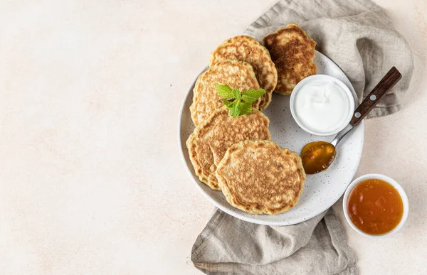 Tasty oatmeal pancakes served with jam and natural yogurt on ceramic plate, light concrete background. — Stock Photo, Image
