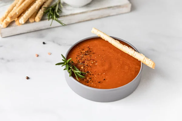 Zuppa di pomodoro guarnire con pepe macinato, rosmarino e bastoncini di pane, sfondo chiaro. — Foto Stock