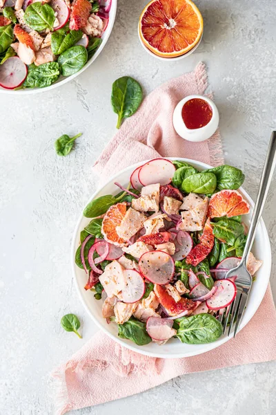 Fresh salad with salmon, spinach, radish and red oranges served with orange sauce, light concrete background. Top view. — стоковое фото