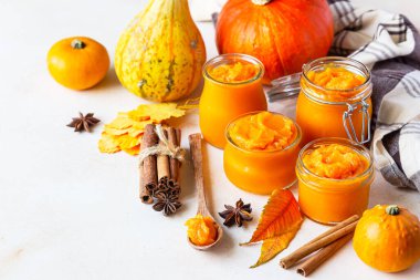 Farklı cam kavanozlarda farklı baharatlar ve taze balkabaklarıyla kabak püresi. Sonbahar ya da kış yemekleri. Işık taşı arkaplanı.