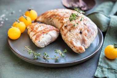 Izgara tavuk ya da hindi göğsü, kiraz domatesli ve kekik yeşil taş zemin üzerinde seramik bir tabakta..