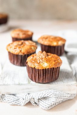 Beyaz kesme tahtasının üzerinde yulaf kırıntıları olan lezzetli kahvaltı çörekleri, açık beton arka plan. Seçici odak.