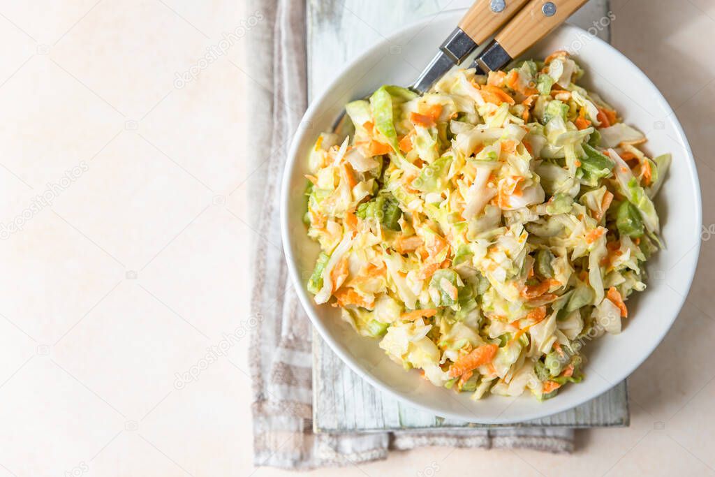 Coleslaw. Salad made of shredded white cabbage, grated carrot and rhubarb with orange mayonnaise dressing in white bowl, light concrete background. Top view.