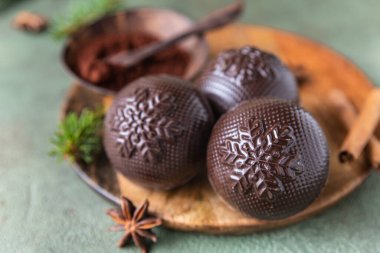 Lezzetli kakao bombaları, marşmelov ve köknar dalları ve baharatlarla dolu ahşap tabakta çikolata. Son moda sıcak kış içeceği. Seçici odaklanma. Kapat..