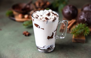 Marshmallow ve kakaolu sıcak çikolata ya da yeşil beton arka planda çikolata bombası. Köknar dalları ve baharatlarla kış kompozisyonu. Seçici odak.